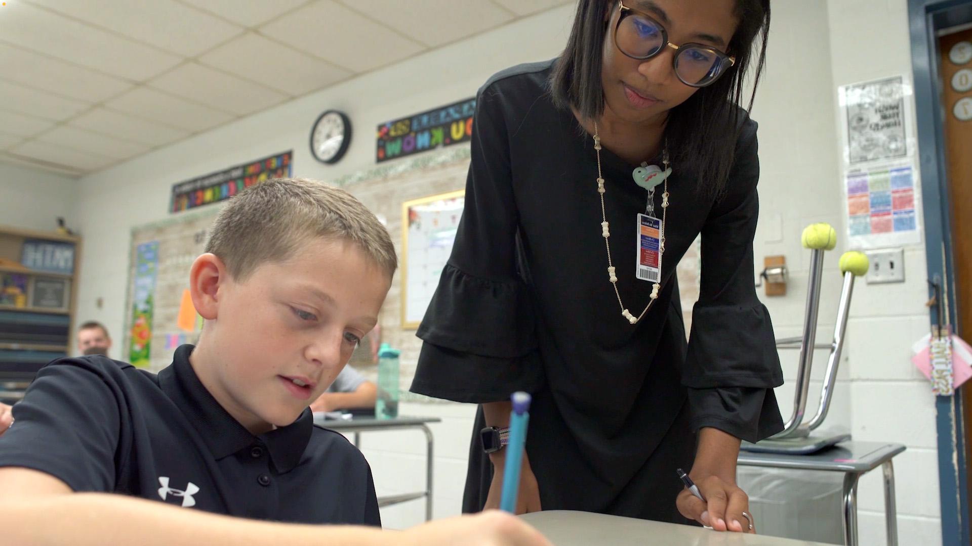 教育 teacher in class with grade school student